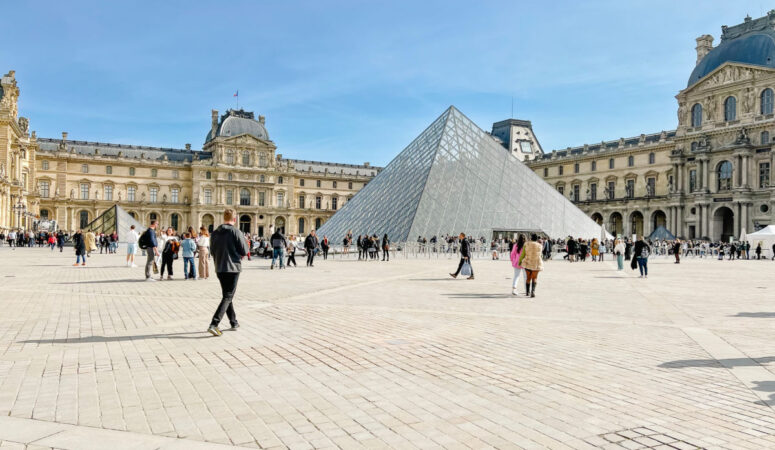 People walking in front of the glass pyramid at the Louvre